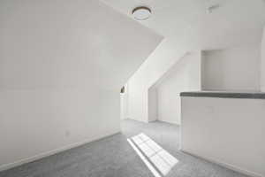 Additional living space with baseboards and light colored carpet