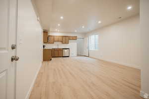 Example of basement - Kitchen with light wood-style floors, stainless steel dishwasher, recessed lighting, wood finish cabinets, and open floor plan