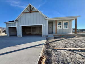 Example: View of front of property featuring board and batten siding, an attached garage, concrete driveway, and covered porch