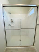 Example: Full bath featuring a shower stall and light tile patterned flooring