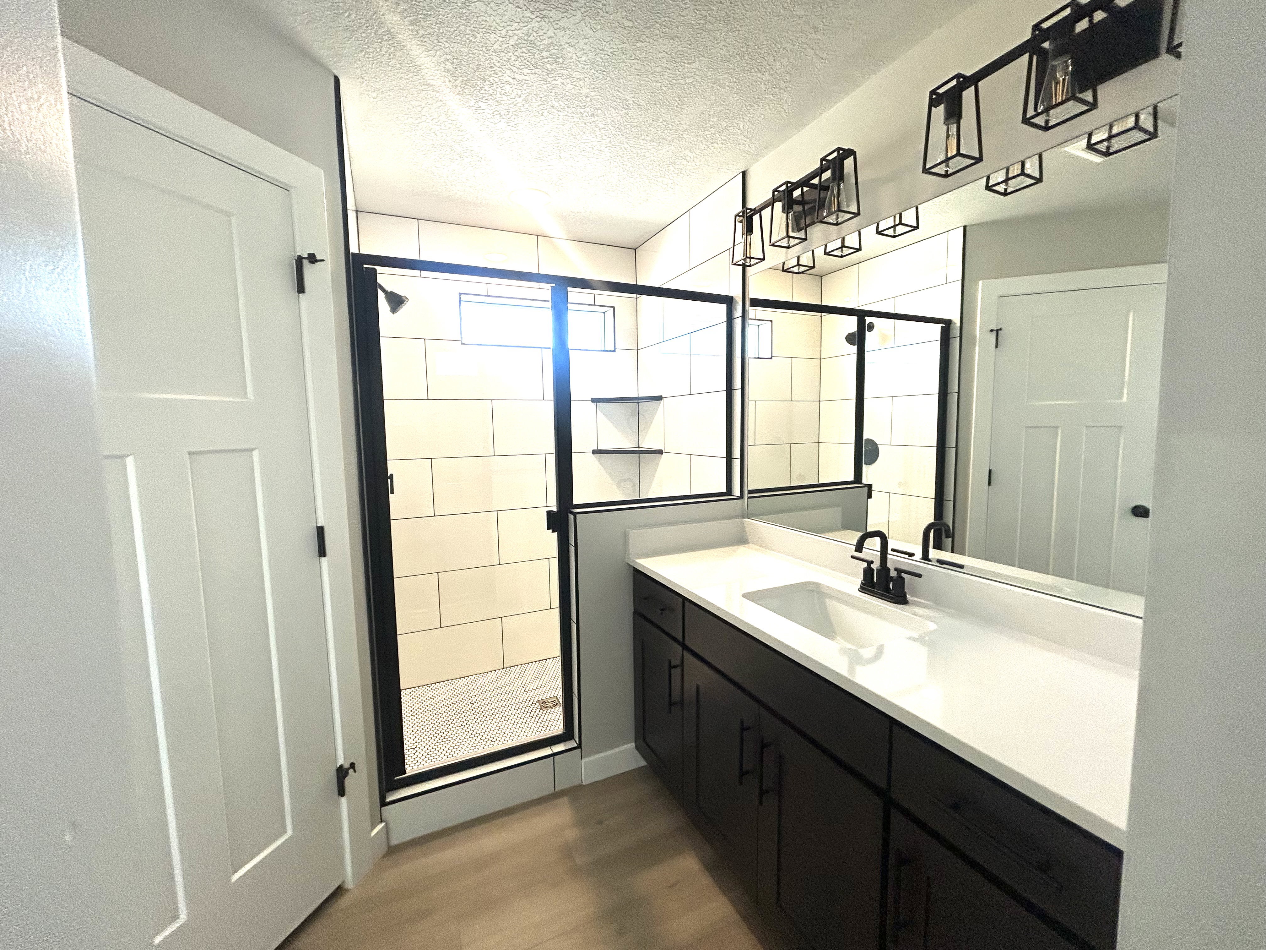 Modern bathroom featuring a double vanity with dark wood cabinetry, white countertop, and black fixtures