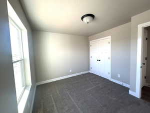 Neutral tone walls with white trim, dark gray carpet, and a large window