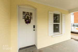 Property entrance featuring covered porch and brick siding