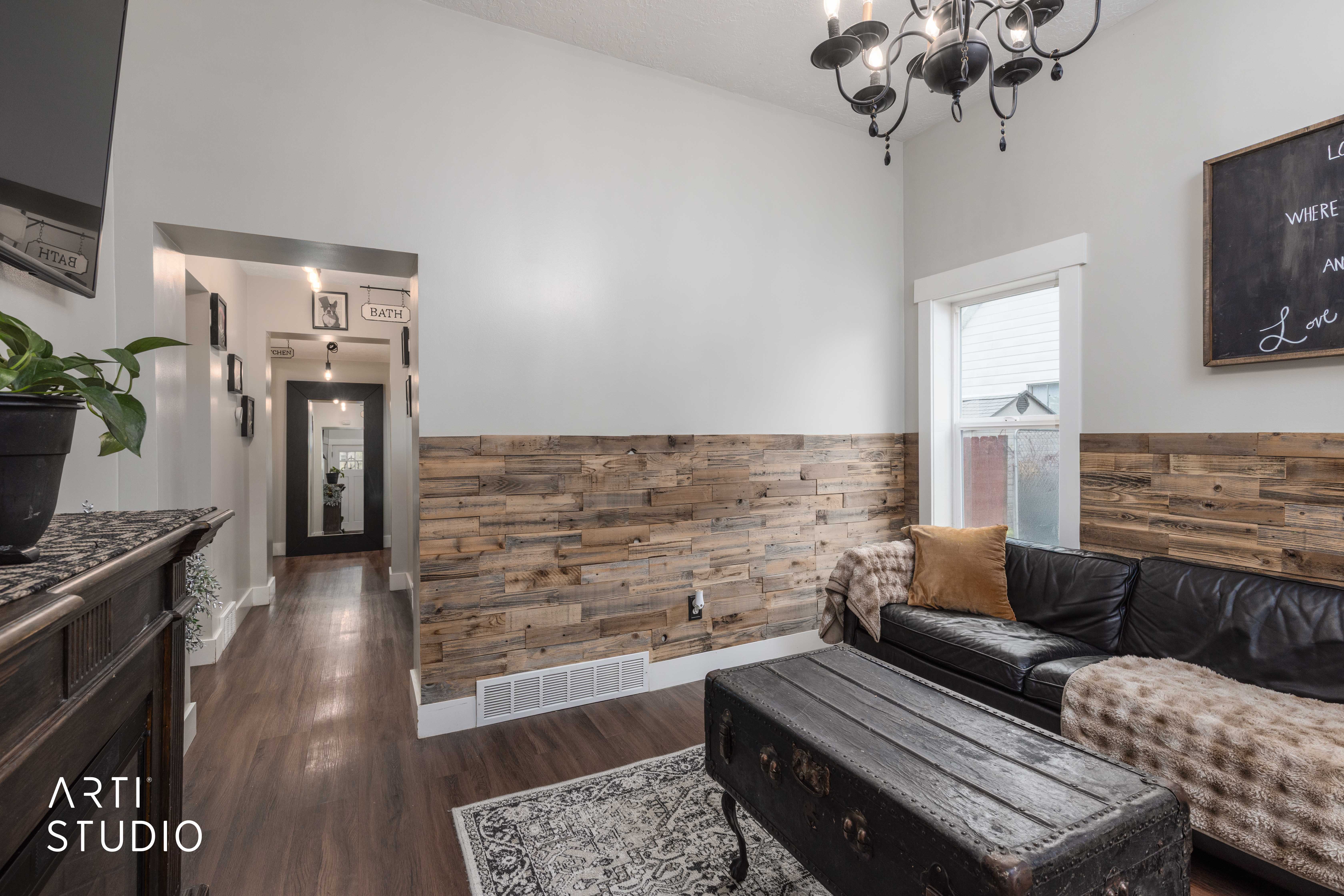 Living room with dark wood-type flooring, wainscoting, wood walls, and suspended lighting