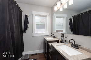 Full bathroom with two vanities, curtained shower, and dark wood-type flooring