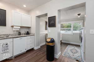 Kitchen featuring white cabinetry, dishwasher, dark wood finished floors, and light stone countertops