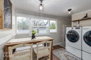 Laundry room featuring independent washer and dryer, dark wood-style flooring, and crown molding