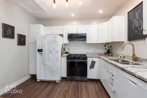 Kitchen featuring white appliances, light stone counters, white cabinetry, dark wood-style floors, and recessed lighting
