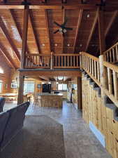 Entry featuring a ceiling fan, a high wood beamed ceiling, rustic walls, log walls, and tile patterned floors