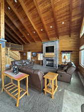 Great Room featuring carpet floors, a high wood beamed ceiling, log walls, and a stone fireplace