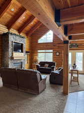Carpeted living area with a high wood beamed ceiling, a stone fireplace, tile patterned flooring, log walls, and french doors