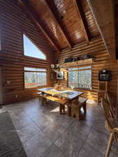 Dining room with a high wood beamed ceiling, healthy amount of natural light, and rustic walls