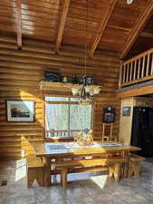 Dining area featuring a high wood beamed ceiling, rustic walls, and a chandelier