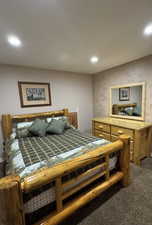 Bedroom featuring dark carpet, recessed lighting, and wallpapered walls