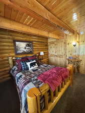 Carpeted bedroom featuring rustic walls and a wood ceiling with exposed beams