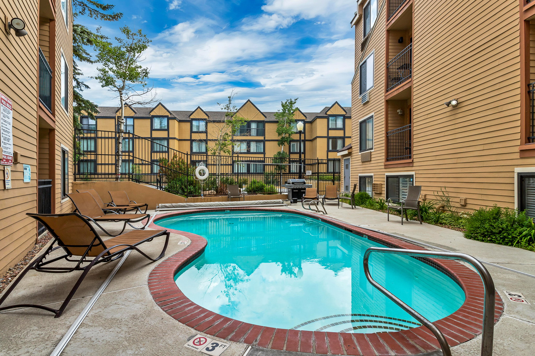 Community pool with a patio area and a grill