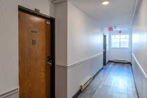Hall with a textured wall, wood finished floors, and a baseboard radiator