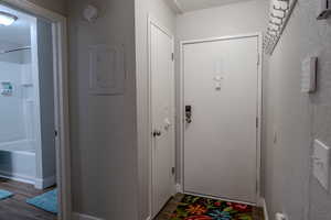 Entryway featuring electric panel, wood finished floors, and a textured wall
