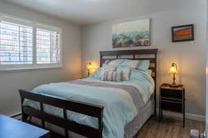 Bedroom featuring a textured wall, wood finished floors, and baseboard heating