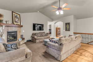 Living room with ceiling fan, arched walkways, a fireplace, and wood finished floors