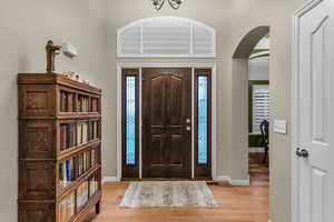 Foyer entrance with arched walkways and light wood-style floors