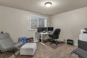 Carpeted office featuring a textured ceiling