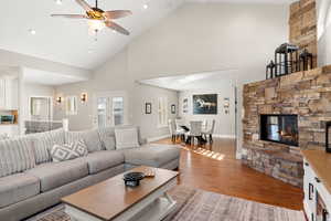 Living room featuring a stone fireplace, wood-type flooring, recessed lighting, a ceiling fan, and lofted ceiling