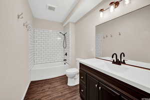 Bathroom with vanity, dark wood-type flooring, and shower / washtub combination