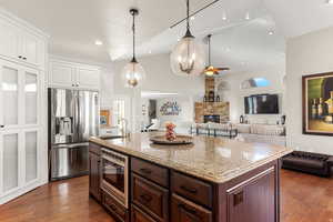 Kitchen with dual tone cabinetry, stainless steel appliances, a ceiling fan, open floor plan, and an island with sink