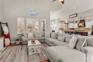 Living room with ceiling fan, wood finished floors, and a high ceiling