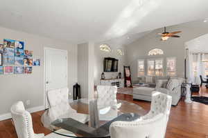 Dining room with hardwood / wood-style floors, ceiling fan, and a high ceiling