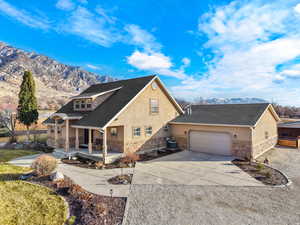 View of front of house featuring stone siding, stucco siding, concrete driveway, a mountain view, and a porch