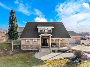View of front of home featuring covered porch, stone siding, stucco siding, a front lawn, and driveway
