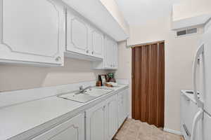 Kitchen featuring white cabinetry, light countertops, and white appliances