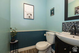 Bathroom with vanity, wainscoting, dark wood finished floors, and tasteful backsplash