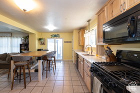 Kitchen featuring black appliances, light countertops, light tile patterned floors, and open floor plan