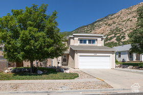 View of front of house with driveway, a garage, a mountain view, and stucco siding
