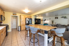Kitchen featuring black appliances, light countertops, open floor plan, light tile patterned flooring, and light wood finish cabinets