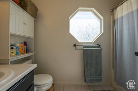 Full bath featuring a shower with curtain, vanity, and light tile patterned flooring