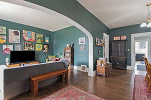 Living area featuring arched walkways, dark wood-style floors, and a chandelier