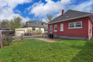 Rear view of property featuring a gate, brick siding, a chimney, a patio area, and a shingled roof