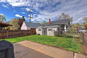 Rear view of house with a storage shed, a fenced backyard, and a chimney