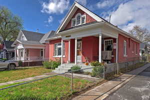 View of front of home with covered porch, a fenced front yard, and roof with shingles