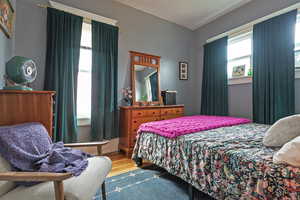 Bedroom with wood finished floors and multiple windows