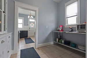 Kitchen featuring plenty of natural light, a chandelier, light tile patterned flooring, and stainless steel appliances