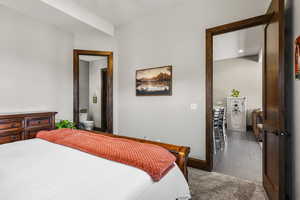 Bedroom featuring connected bathroom, light carpet, and light tile patterned flooring