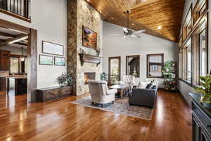 Living room featuring a vaulted wood ceiling, a fireplace, dark wood-type flooring, a ceiling fan, and recessed lighting