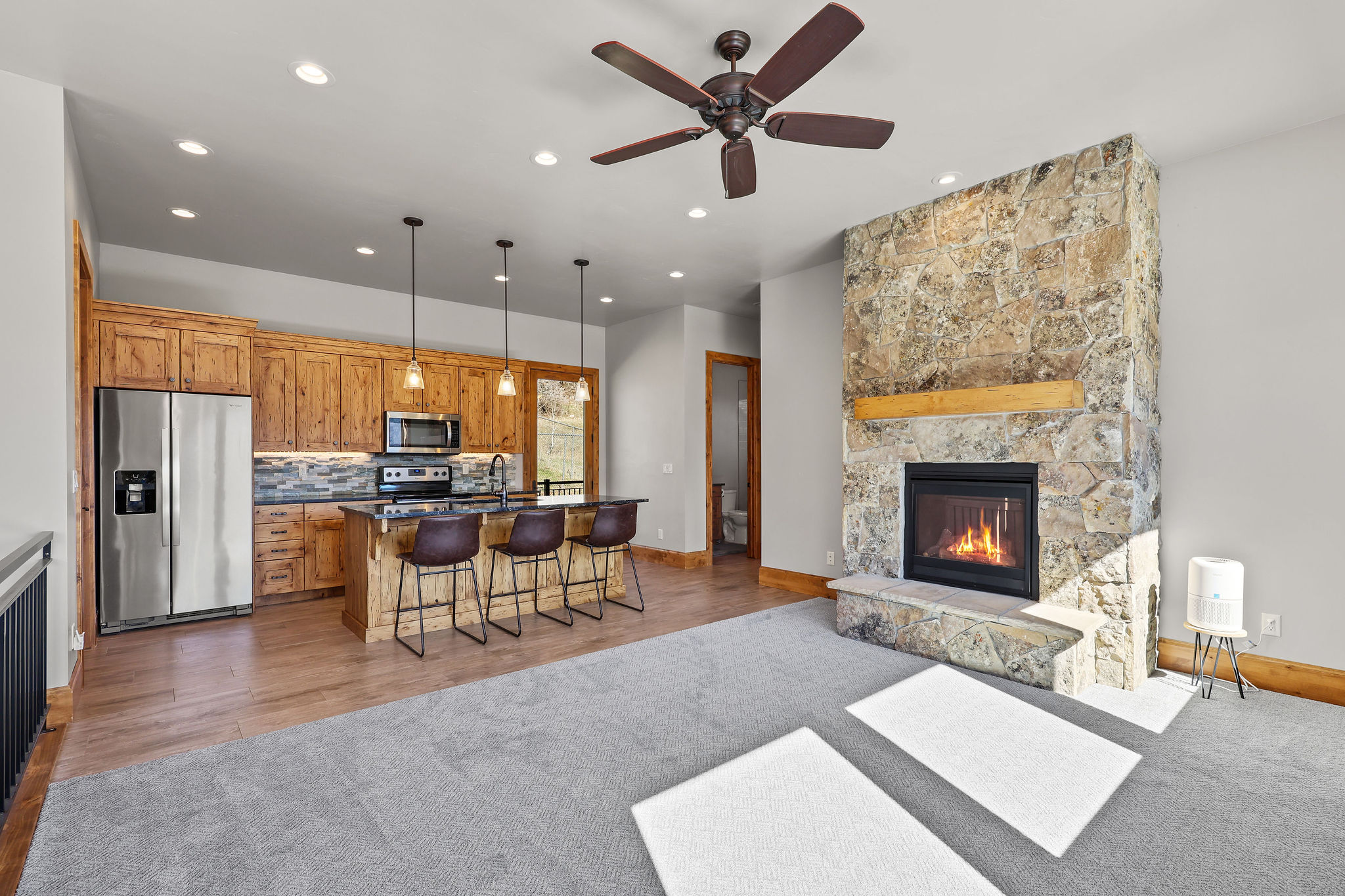 Kitchen featuring open floor plan, stainless steel appliances, wood finish cabinets, a fireplace, and an island with sink