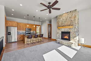 Kitchen featuring open floor plan, stainless steel appliances, wood finish cabinets, a fireplace, and an island with sink