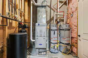 Utility room featuring strapped water heater and heating unit